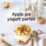 Apple pie parfait made in a jar with layers of yogurt, spiced diced fresh apple, and granola, eaten with a spoon and served with freshly grated nutmeg