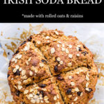 Golden brown loaf of homemade Irish soda bread with raisins and rolled oats scored into 4 sections