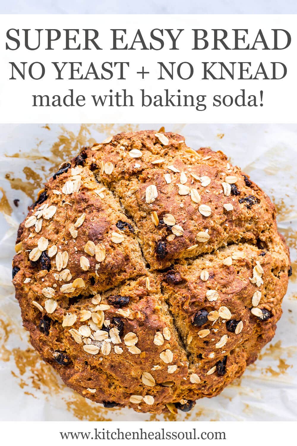 Irish soda bread with raisins topped with oats and scored with a big X on top, on parchment paper