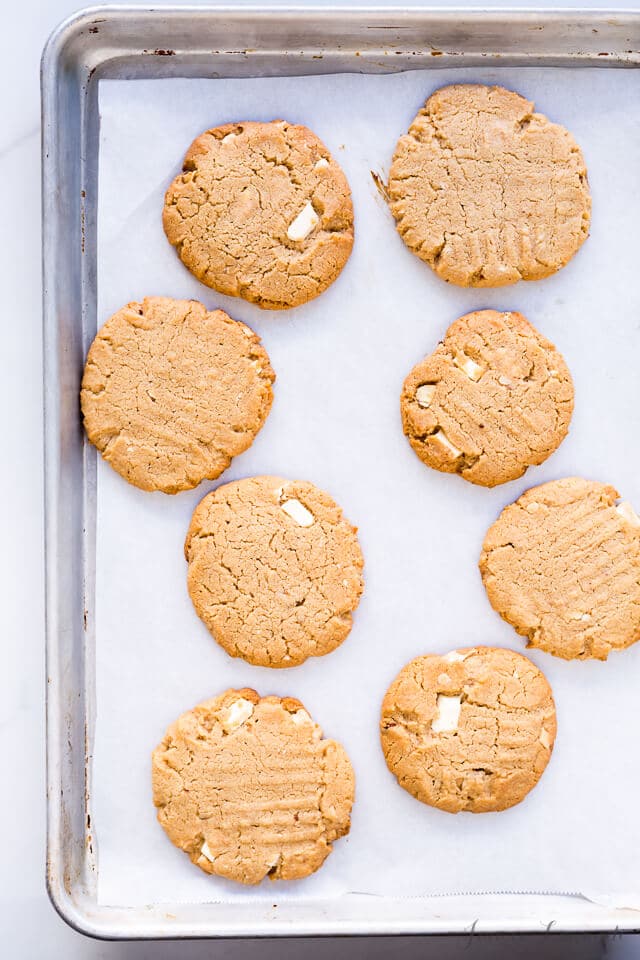 Chewy peanut butter and white chocolate chunk cookies on a sheet pan.