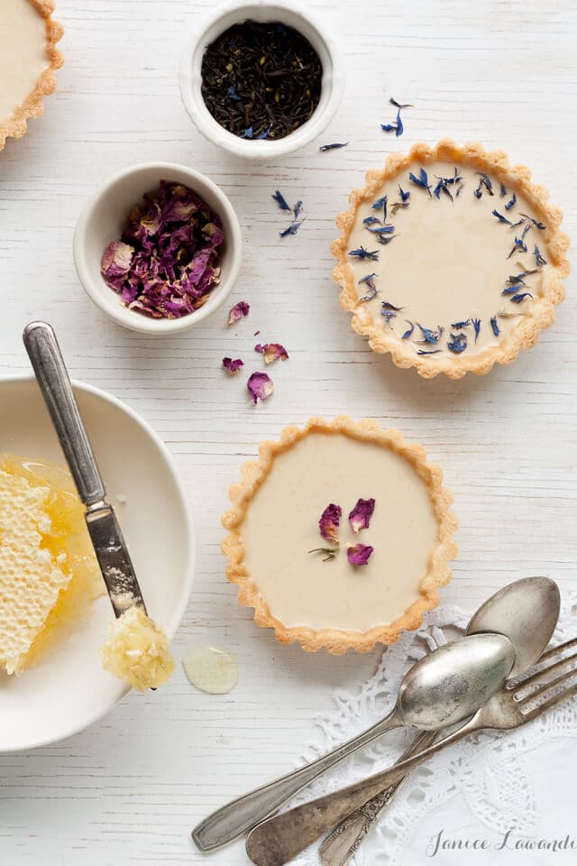 Little Earl Grey panna cotta tarts decorated with dried rose petals and dried cornflowers, served with honeycomb