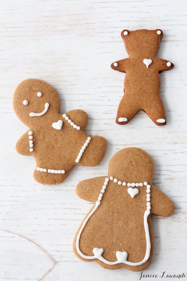 Decorated gingerbread cookie cutouts of a boy, a girl, and a teddy bear.