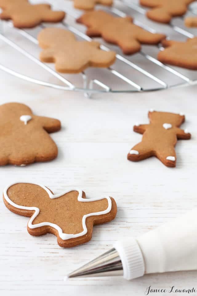 Decorating gingerbread cookie cutouts with a piping bag of royal icing.