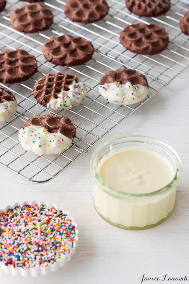 Dipping chocolate cookies in white chocolate and sprinkles