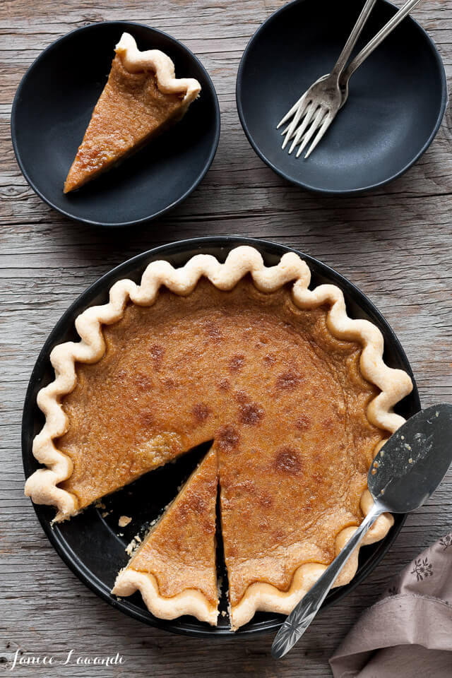 Maple syrup pie sliced and served with a pie lifter on black matte dishes