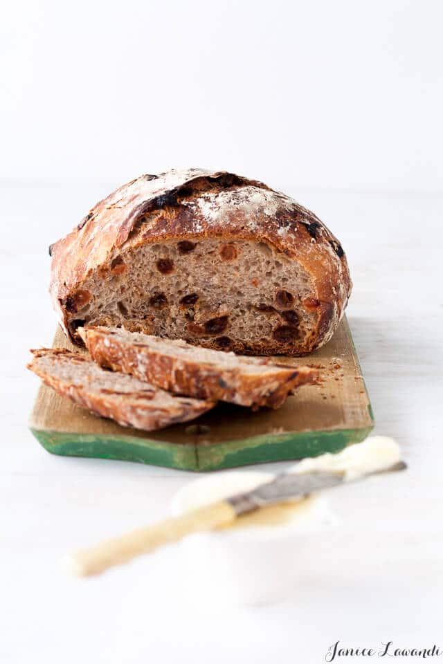 homemade cinnamon raisin bread sliced on a wood cutting board and served with butter and a butter knife