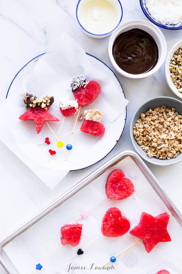 Frozen watermelon pops dipped into melted chocolate and granola or other fun toppings