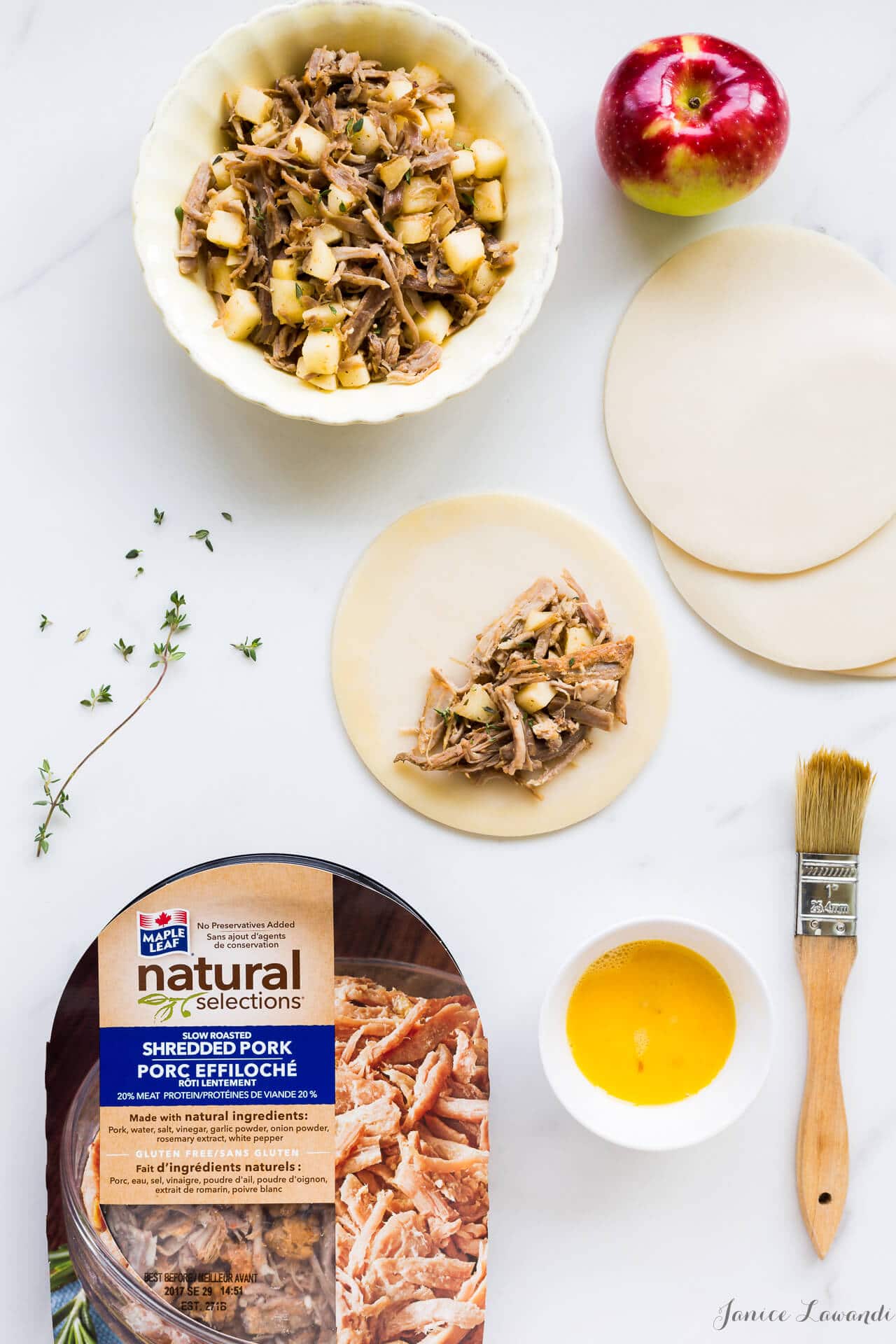 Making savoury pies, filling them with a mixture of pork and apple with fresh thyme, brushing the edges of the pastry with egg to seal the hand pies