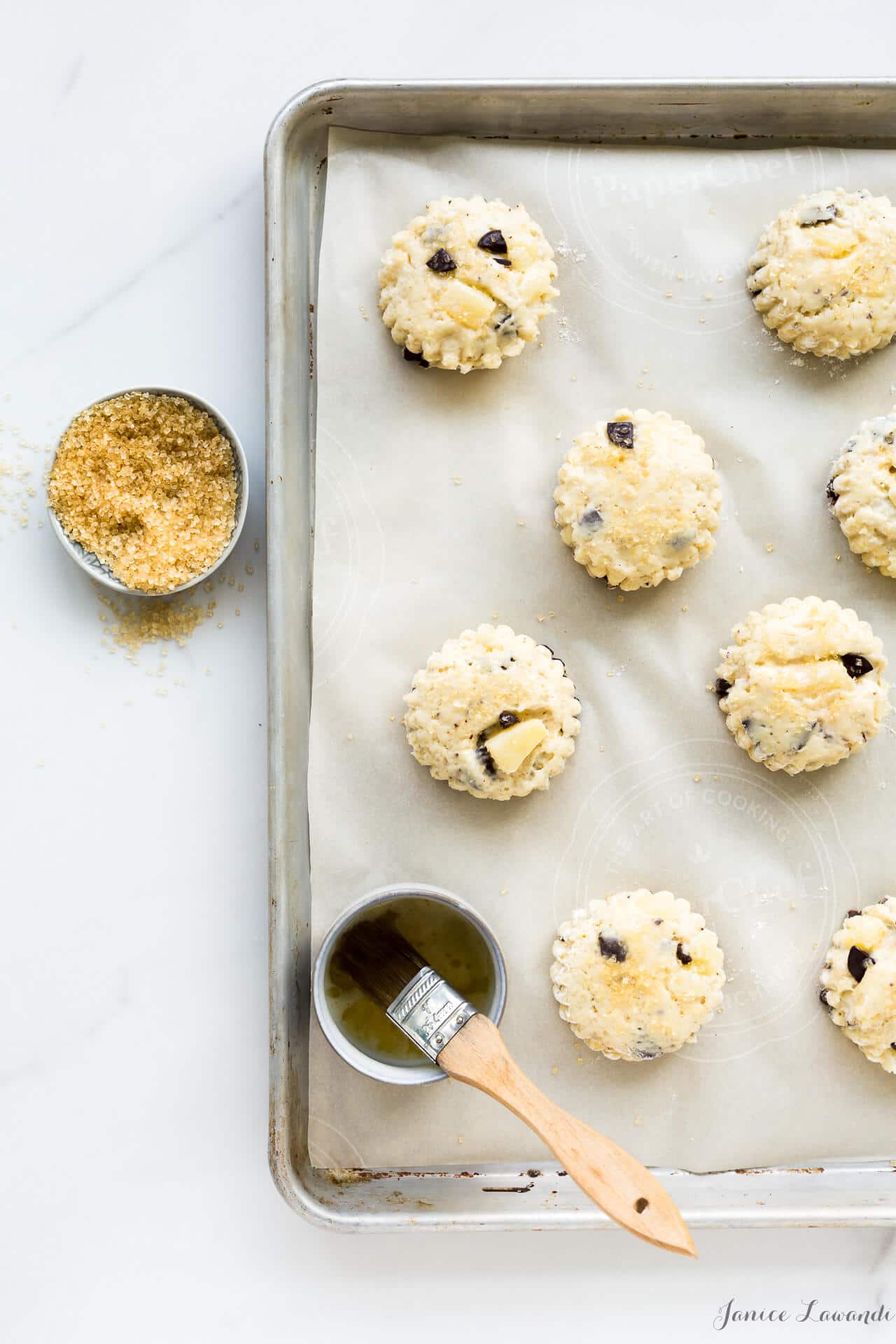 Pear chocolate scones brushed with butter and sprinkled with turbinado before baking on a parchment-lined sheet pan