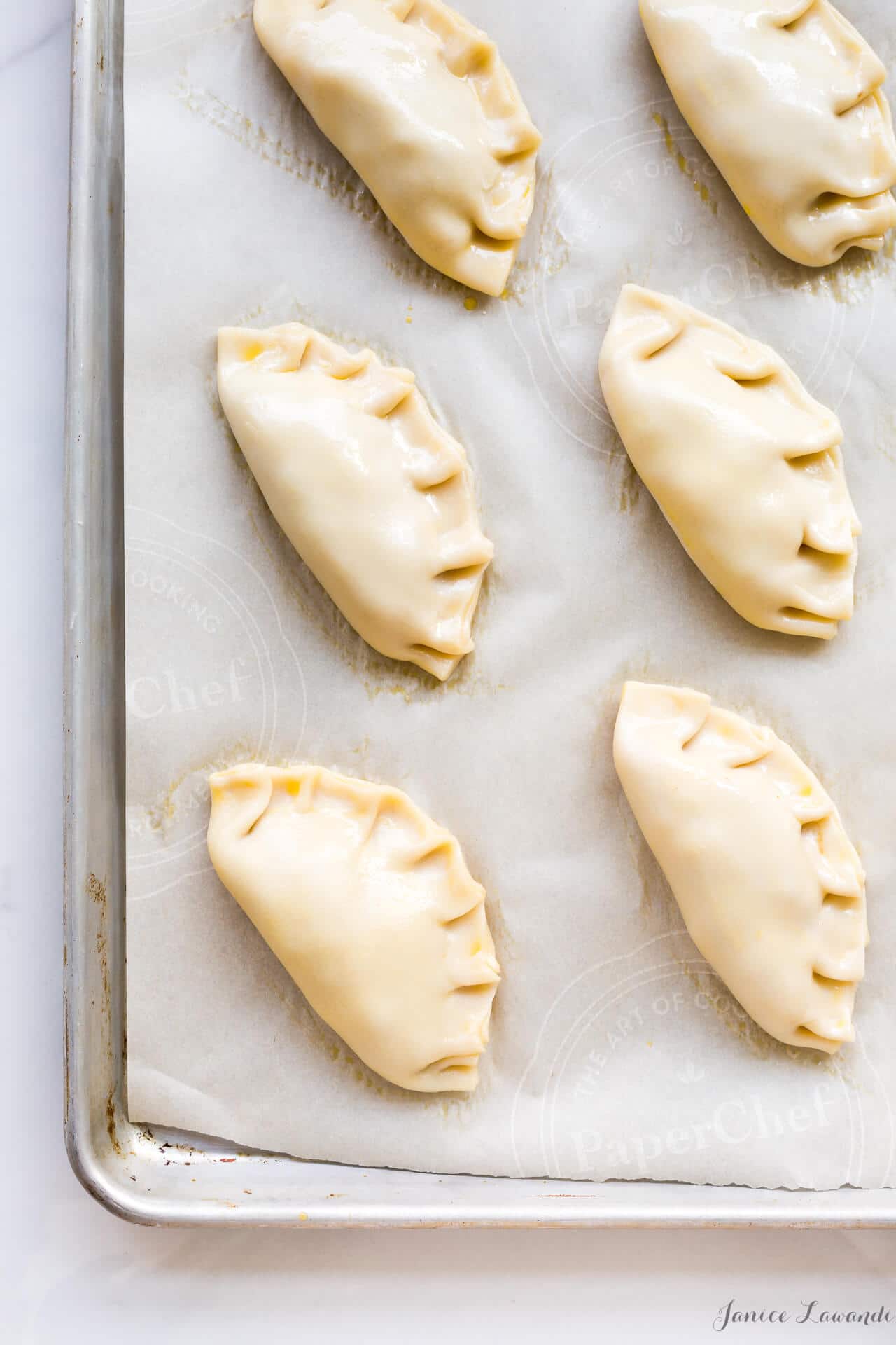 Savoury pork and apple pies ready for the oven filled with shredded pork, chunks of apple, and fresh thyme