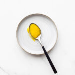 A spoonful of bright yellow homemade lemon curd on a ceramic plate.