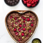 Brownies baked with walnuts and topped with raspberries and pumpkin seeds and baked in a heart shaped pan