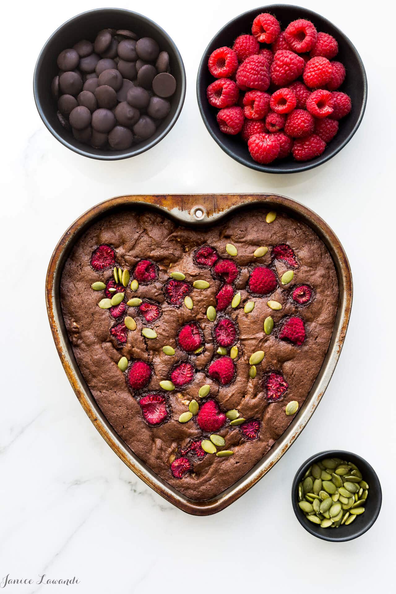 Brownies baked with walnuts and topped with raspberries and pumpkin seeds and baked in a heart shaped pan