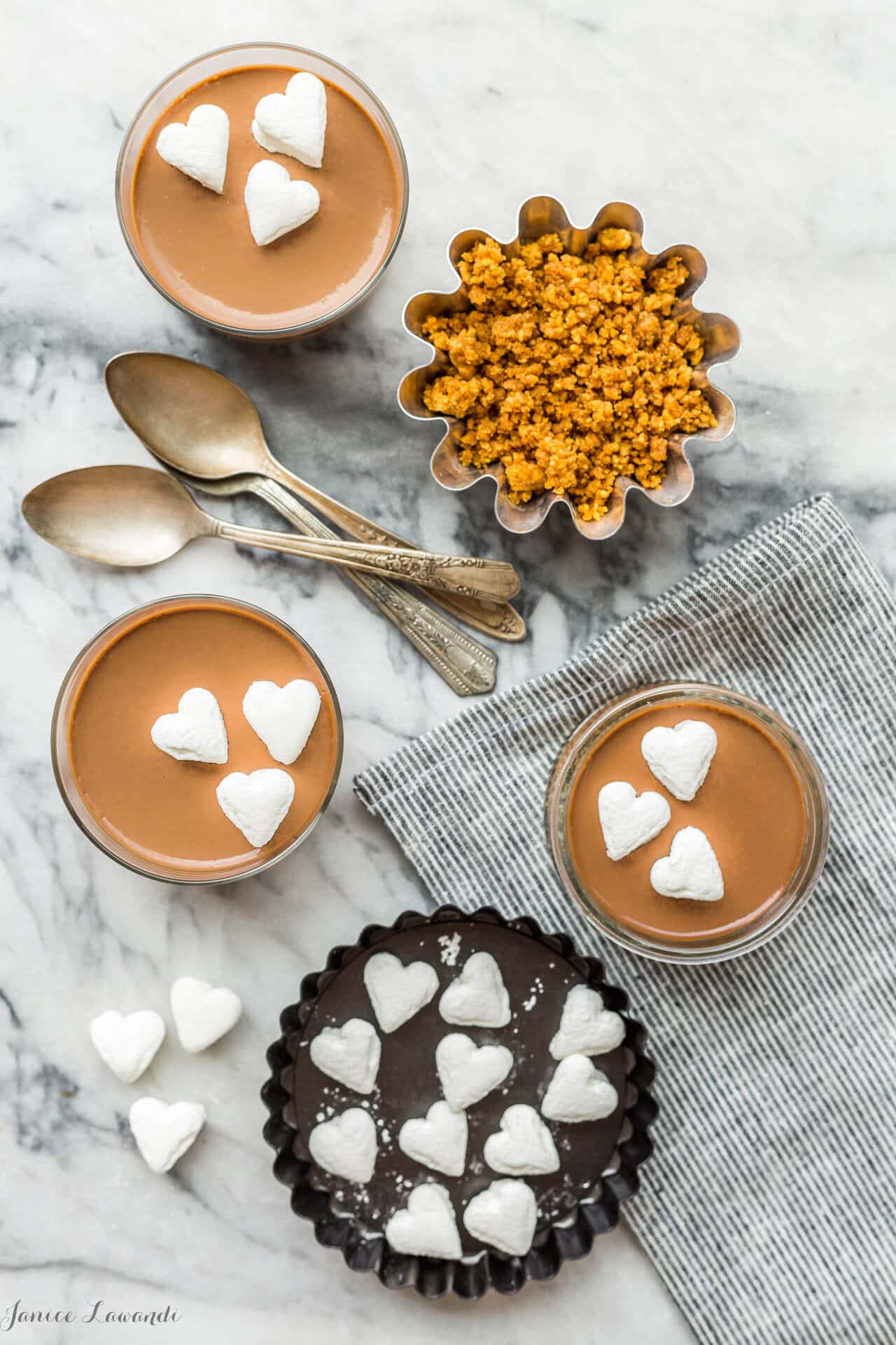 Jars of milk chocolate pots de crème served like s'mores with graham cracker cookie crumbs and marshmallows on top.