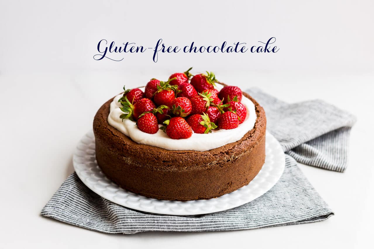 Moist gluten-free chocolate cake with buckwheat flour and ground almond topped with whipped cream and fresh strawberries