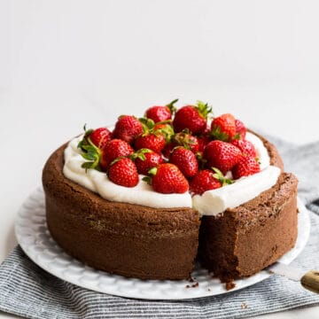 Single layer gluten free chocolate cake topped with whipped cream and fresh strawberries