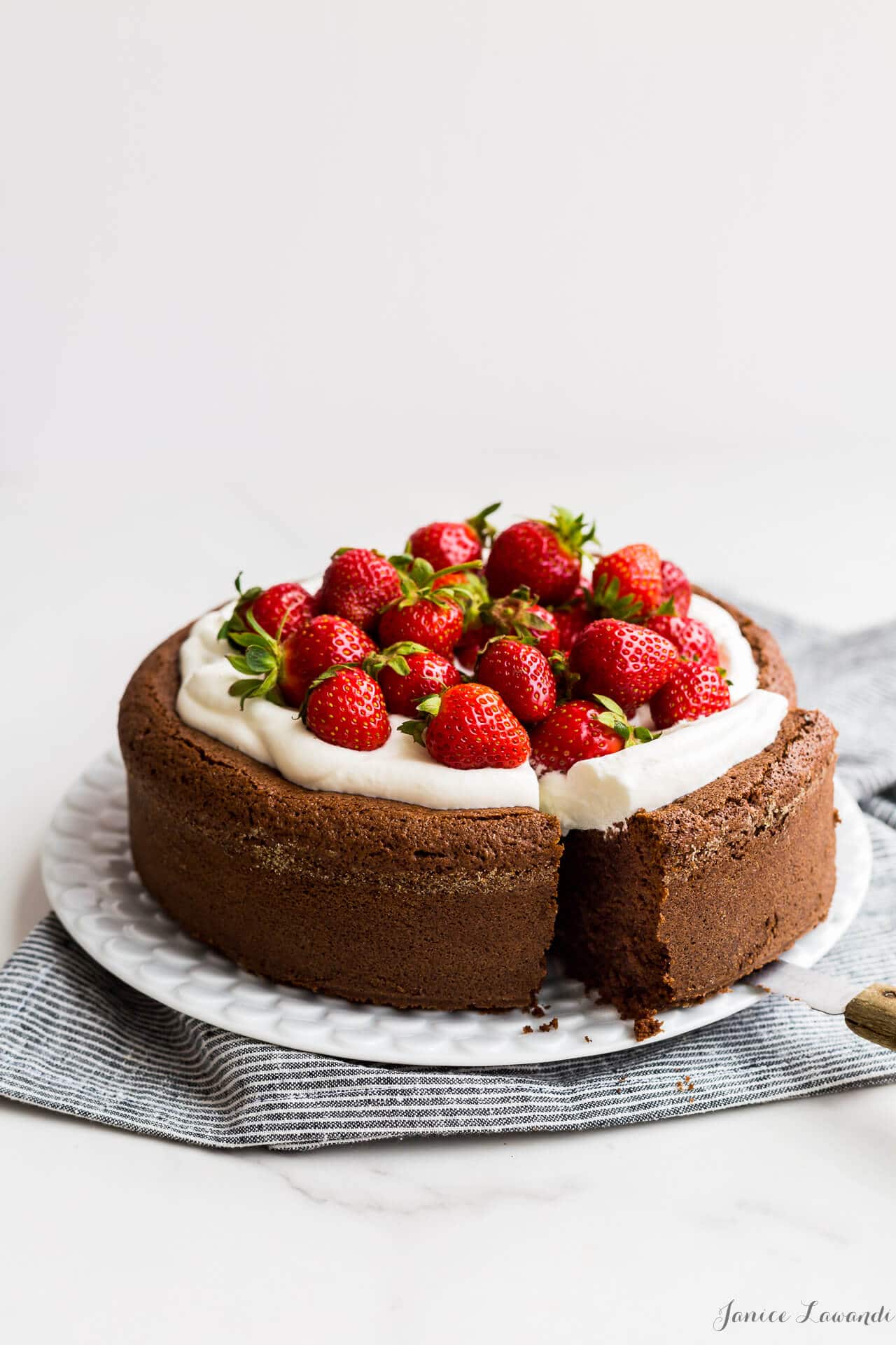 Single layer gluten free chocolate cake topped with whipped cream and fresh strawberries