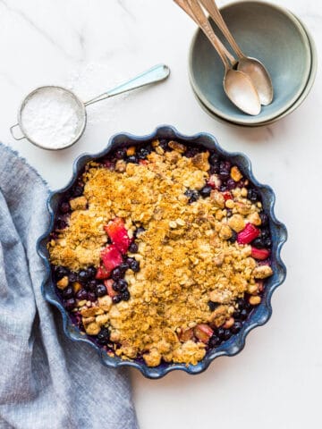 Bluebarb or blueberry rhubarb crumble with a marzipan oat crumble topping in a blue baking dish with a fluted edge