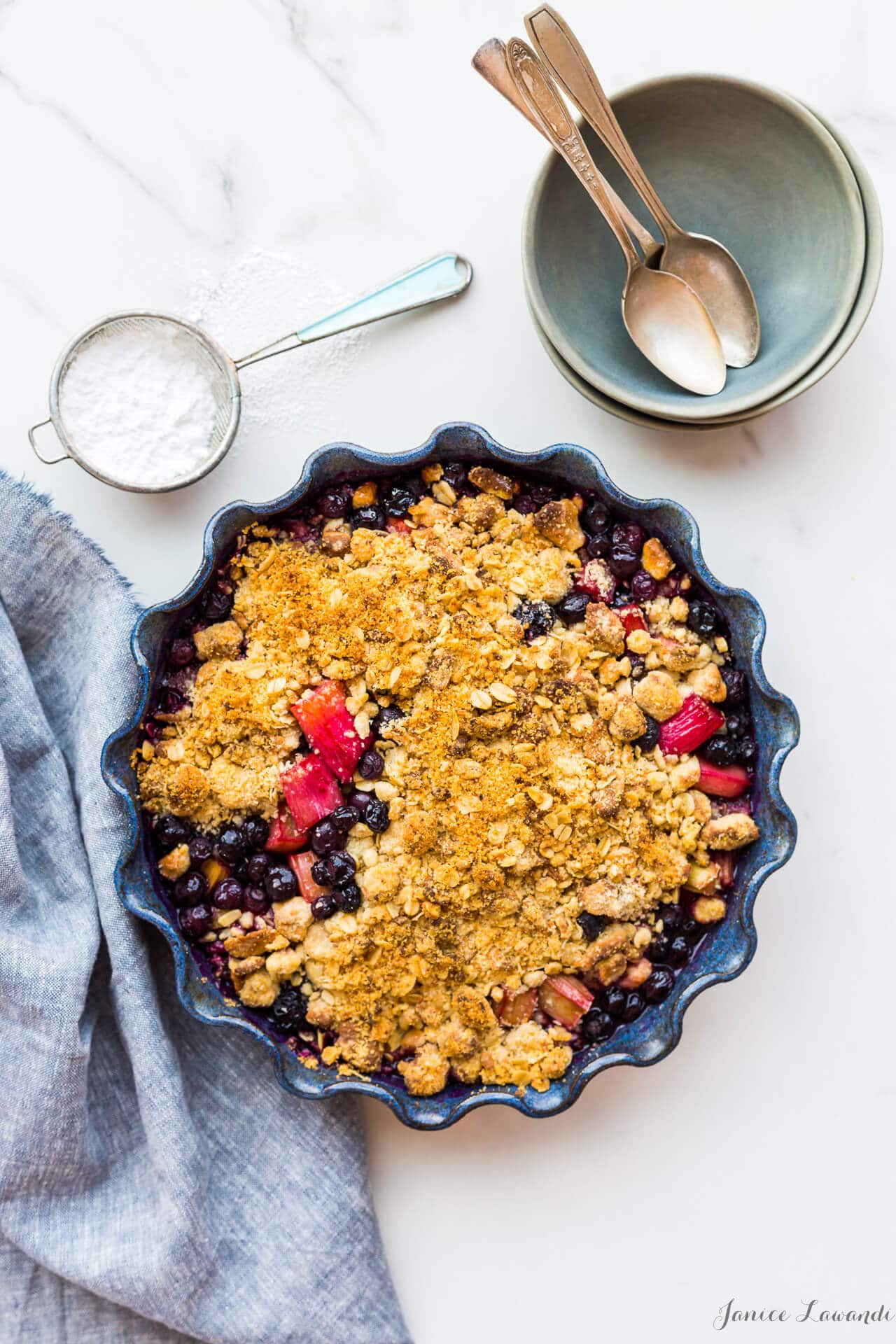 Bluebarb or blueberry rhubarb crumble with a marzipan oat crumble topping in a blue baking dish with a fluted edge