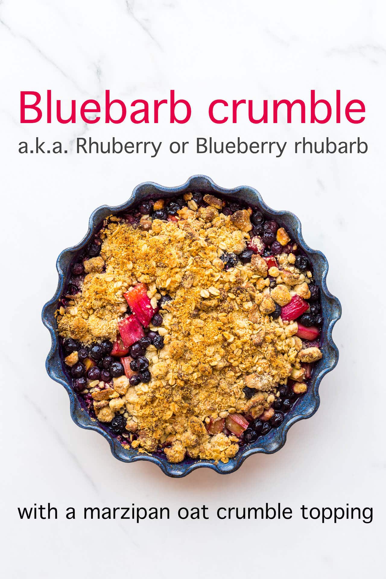 Blueberry rhubarb crumble with a marzipan oat crumble topping served in a round ceramic blue baking dish with a fluted edge