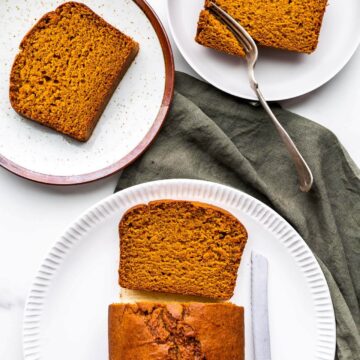 Slicing pumpkin loaf cake to serve on ceramic plates with green linen.