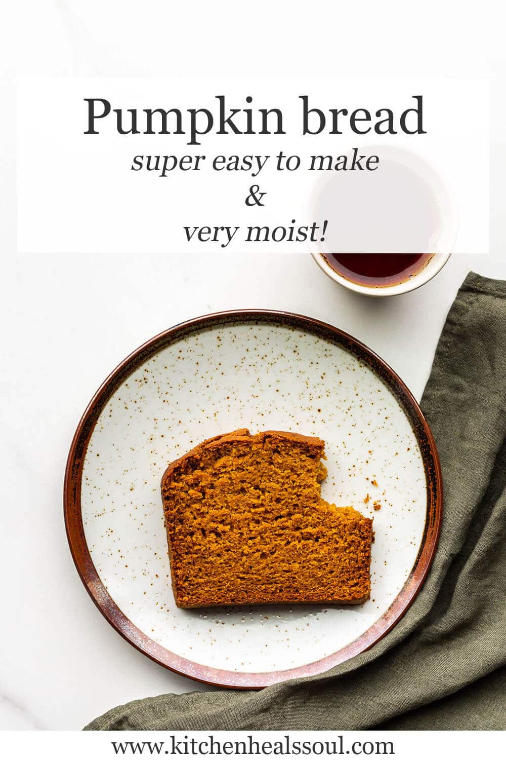 A slice of pumpkin bread on a ceramic plate with a green linen and a cup of tea