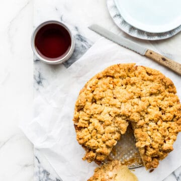 Apple crumb coffee cake ready to be served with cups of tea, plates and a serrated knife