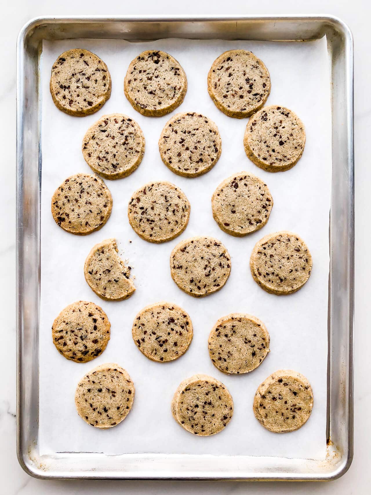 A rimmed baking sheet of shortbread cookies, lined with parchment so the cookies don't stick.