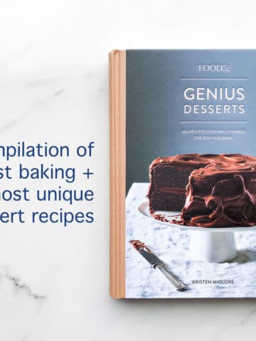 The cover of the Food52 Genius Desserts cookbook features a two layer chocolate cake with chocolate frosting on a cake stand