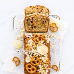 Christina Tosi's compost pound cake rectangular loaf cake with potato chips, pretzels, chocolate chips, butterscotch chips, oats, and coffee, on a small cooling rack on parchment paper