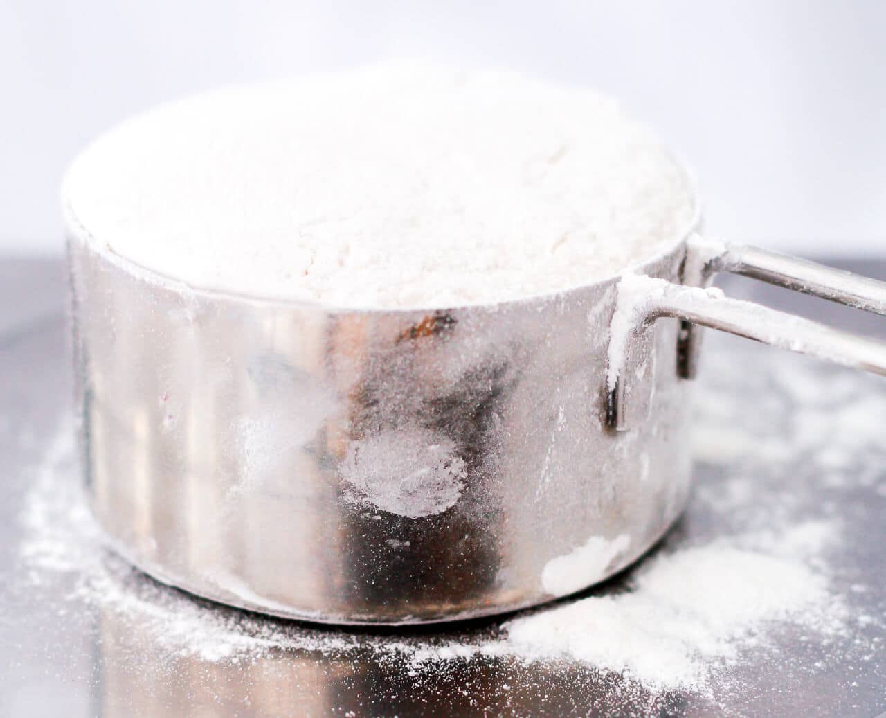 A dry measuring cup filled with flour