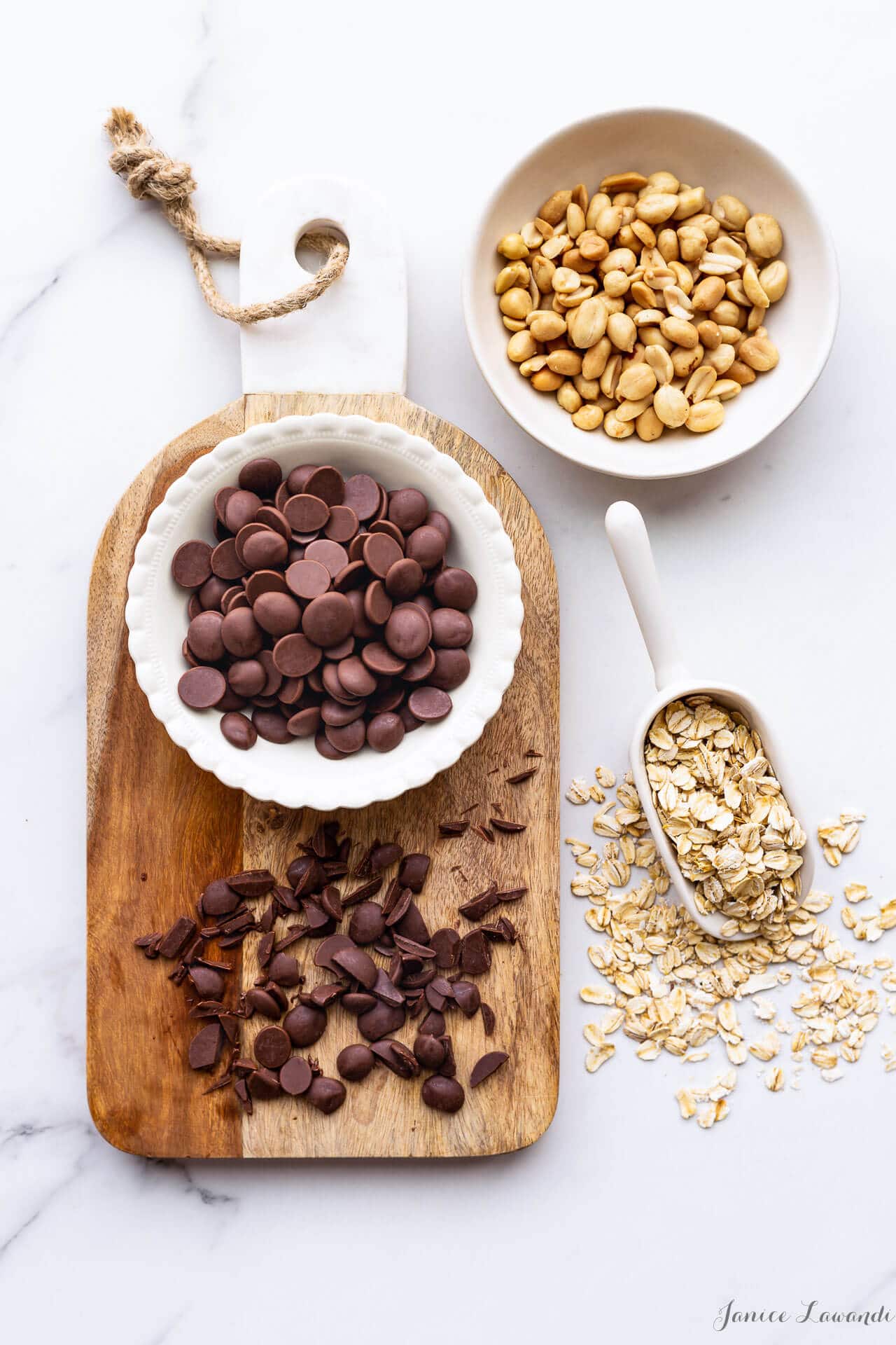 Ingredients for chewy chocolate oatmeal cookies with salted peanuts, milk chocolate chunks, and a scoop of rolled oats