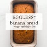 Loaf of eggless banana bread (vegan and dairy-free) in loaf pan on marble surface