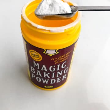 a yellow plastic container of Magic baking powder with 1 teaspoon scooped