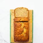 Golden brown banana bread on a vintage wood cutting board with painted green trim