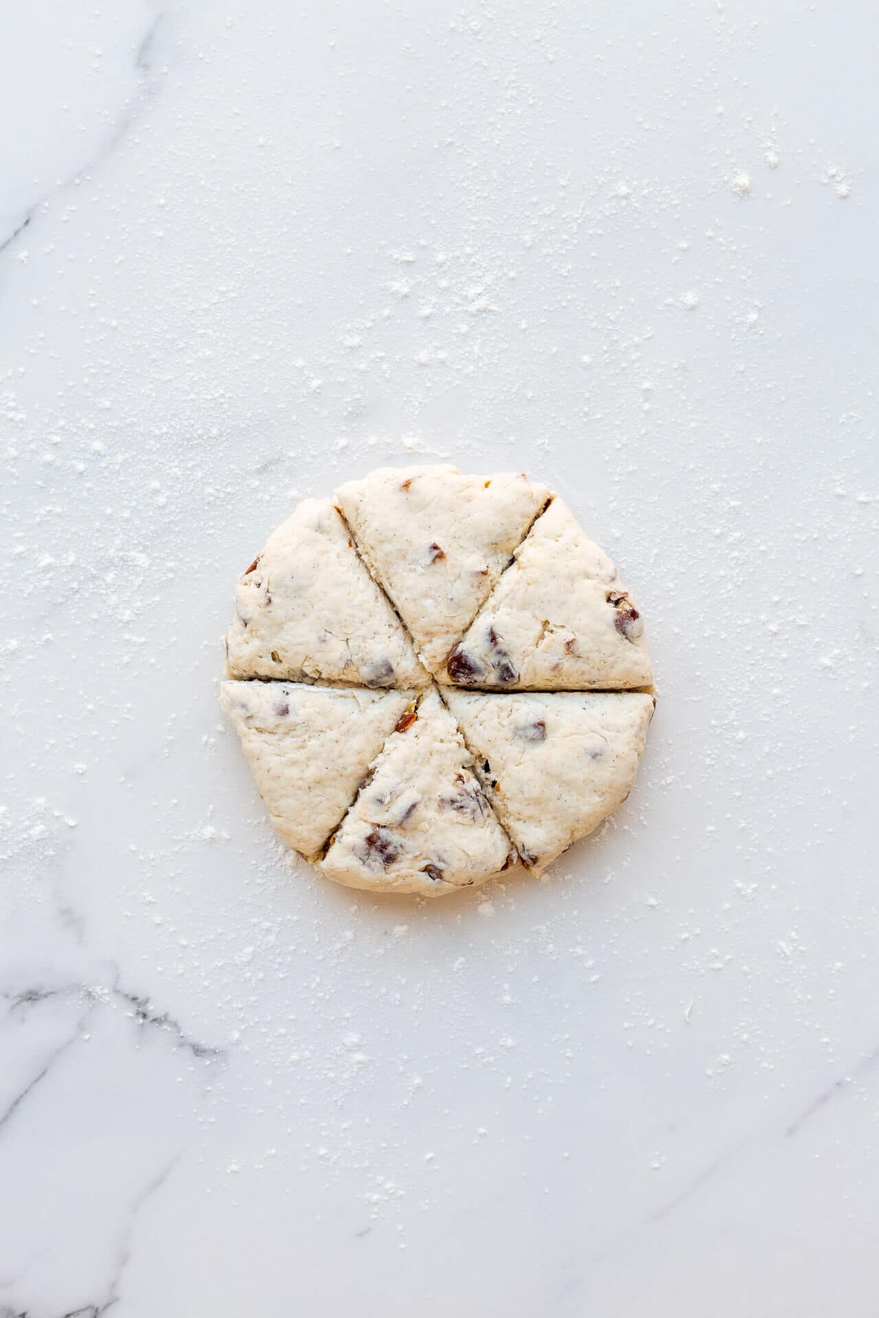 Cutting fruit scones into wedges from a disk of date scone dough