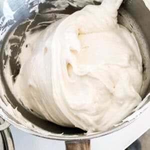 Photo demonstrating folding of whipped egg whites with flour to make angel food cake without deflating the mixture, in a big metal bowl using a large spatula