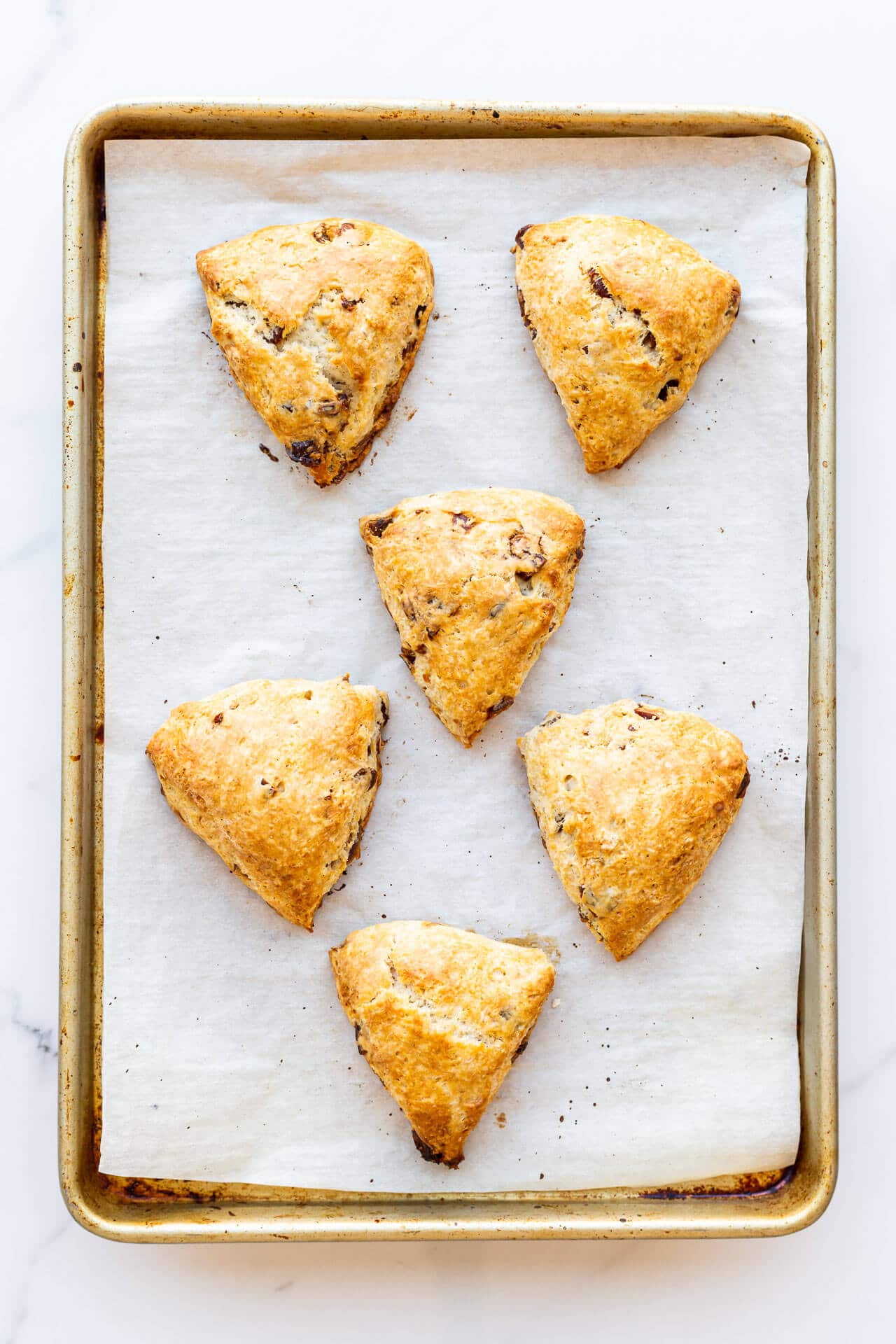 Parchment-lined sheet pan with 6 triangle wedge fruit scones, unglazed
