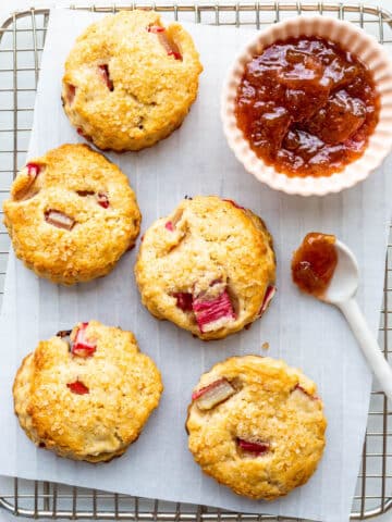 A cooling rack with rhubarb scones and a bowl of jam.