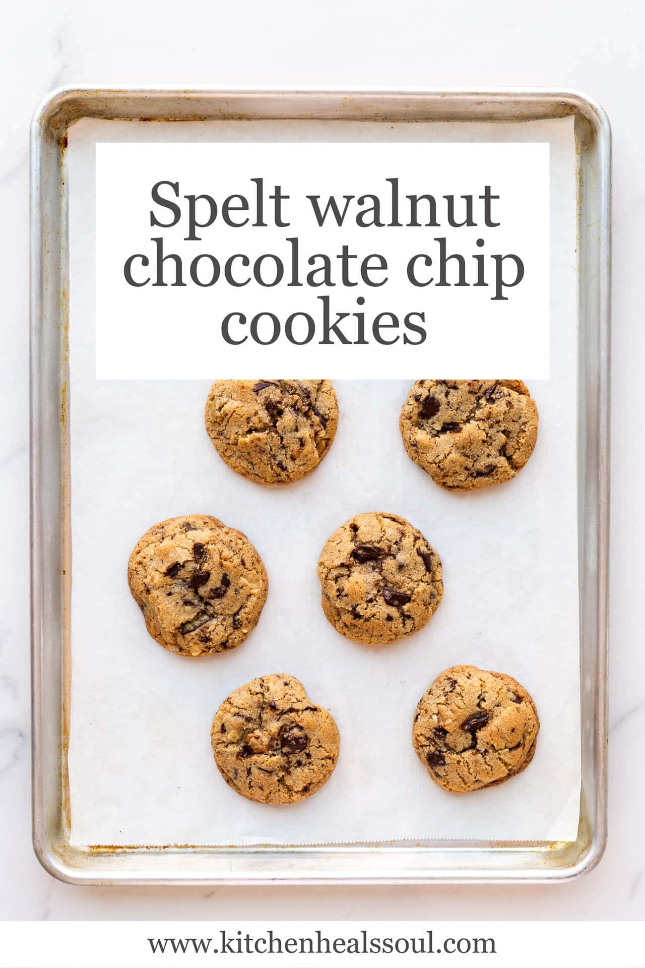 A sheet pan lined with parchment with baked thick chocolate chunk cookies (golden brown on the edges)