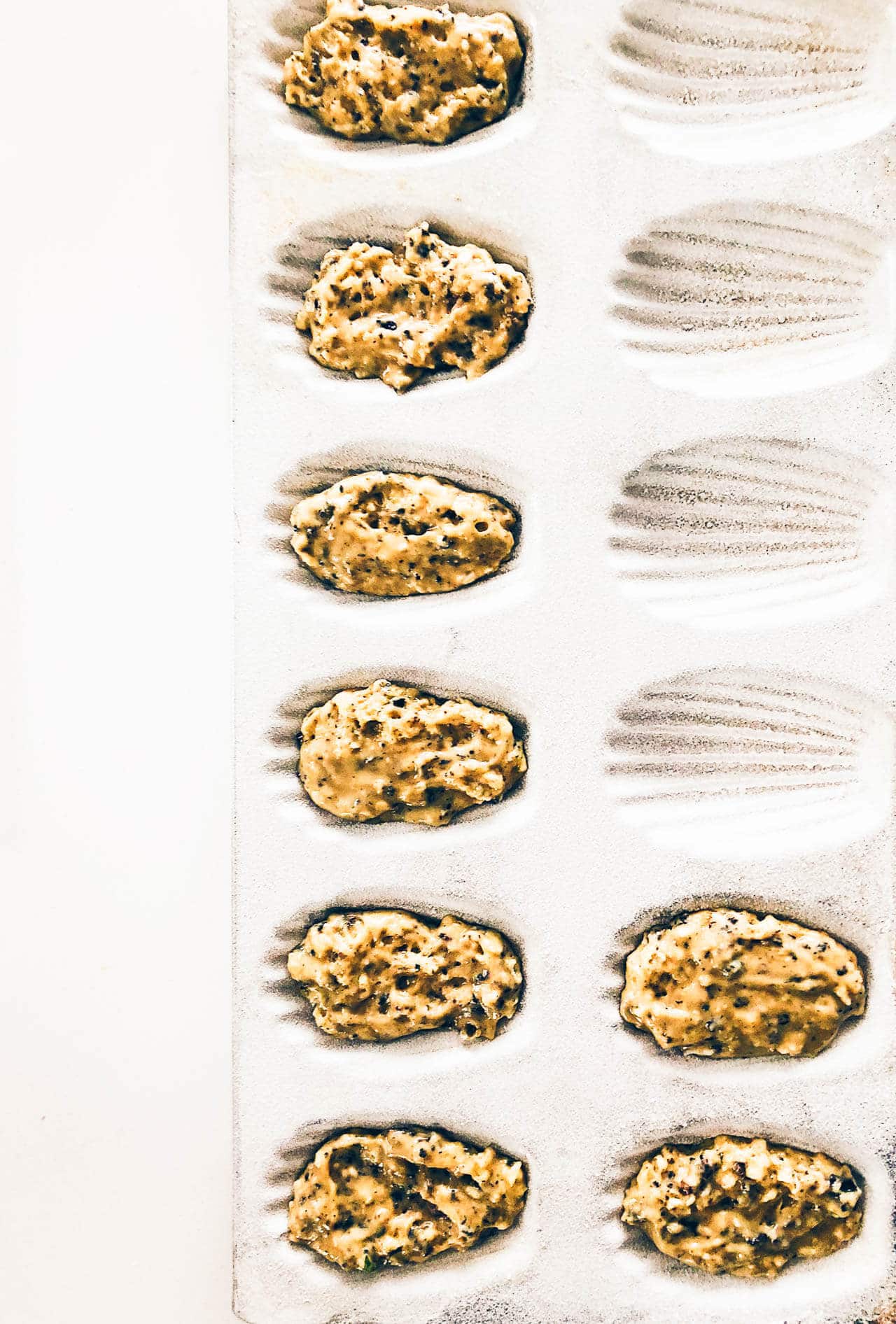 Dividing batter in the greased and floured wells of a madeleine pan