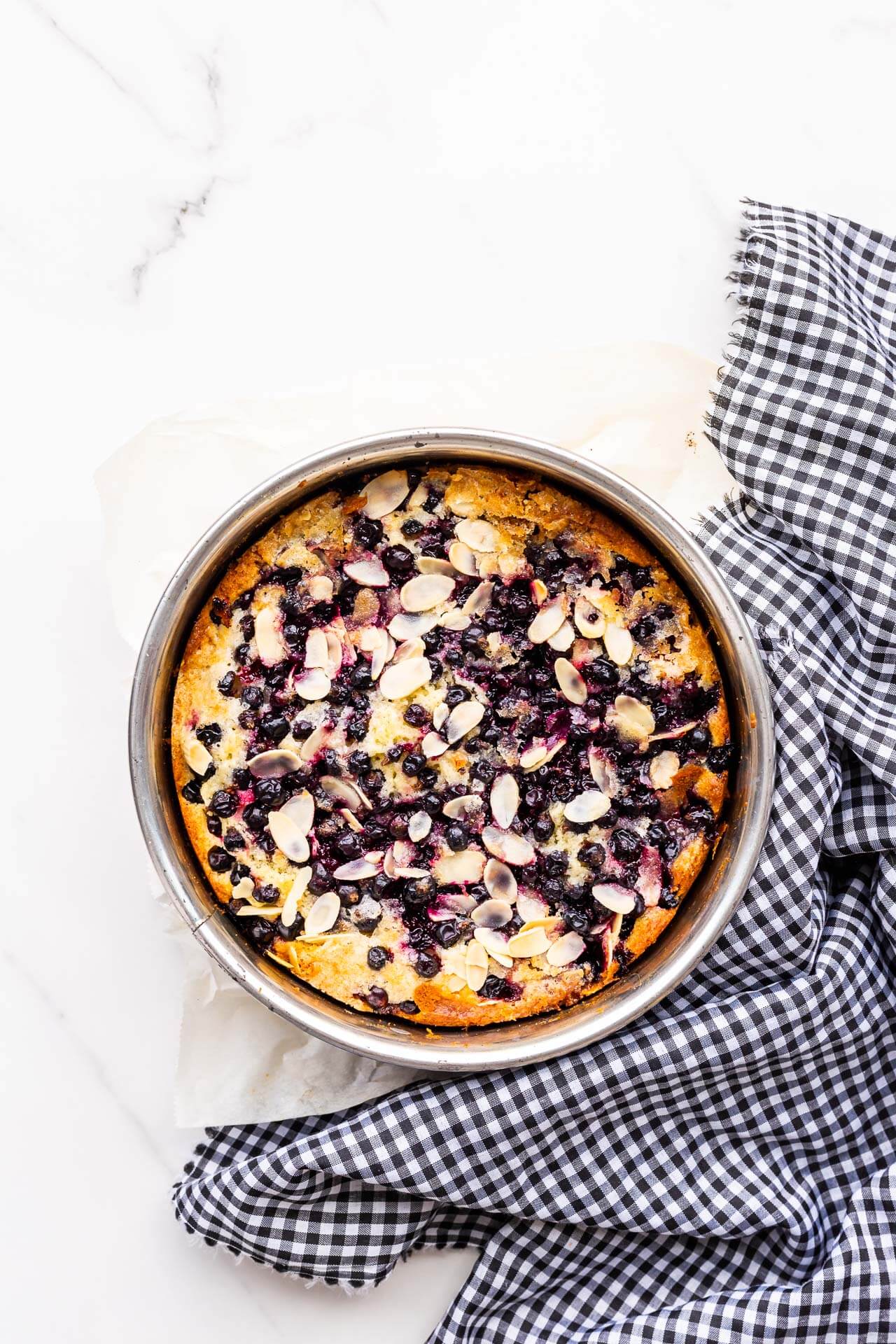 Freshly baked black currant cake in cake pan with checkered linen