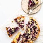 Black currant cake sliced into pieces with one on a speckled ceramic plate with a fork