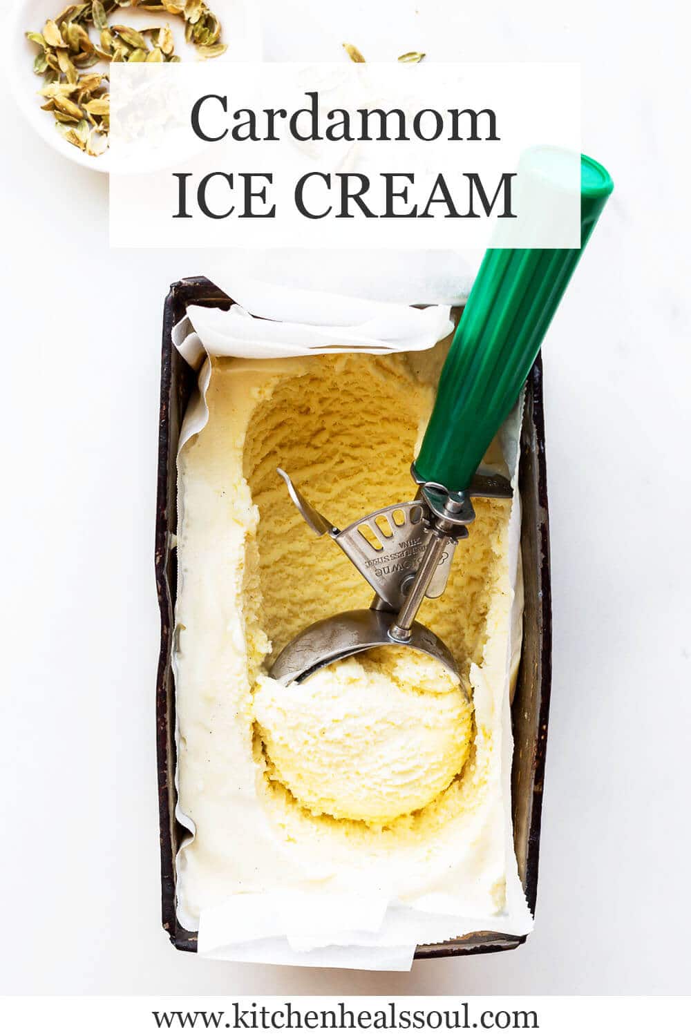 Cardamom ice cream in a loaf pan being scooped with a disher