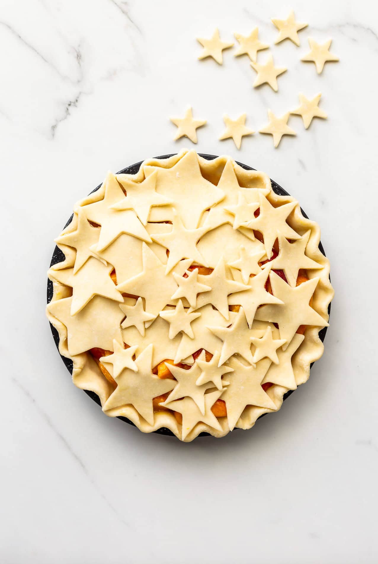 Decorating a pie before baking with star cutouts of pie dough