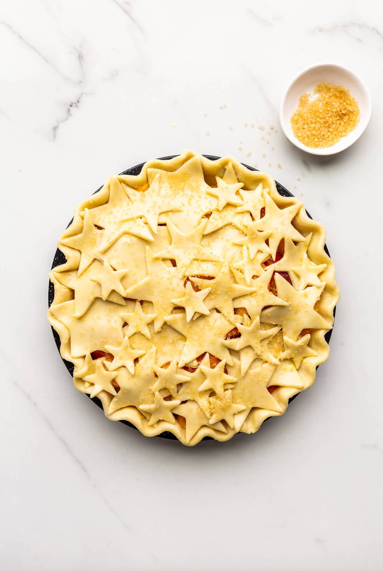 Unbaked pie decorated with star cutouts and sprinkled with turbinado sugar before baking