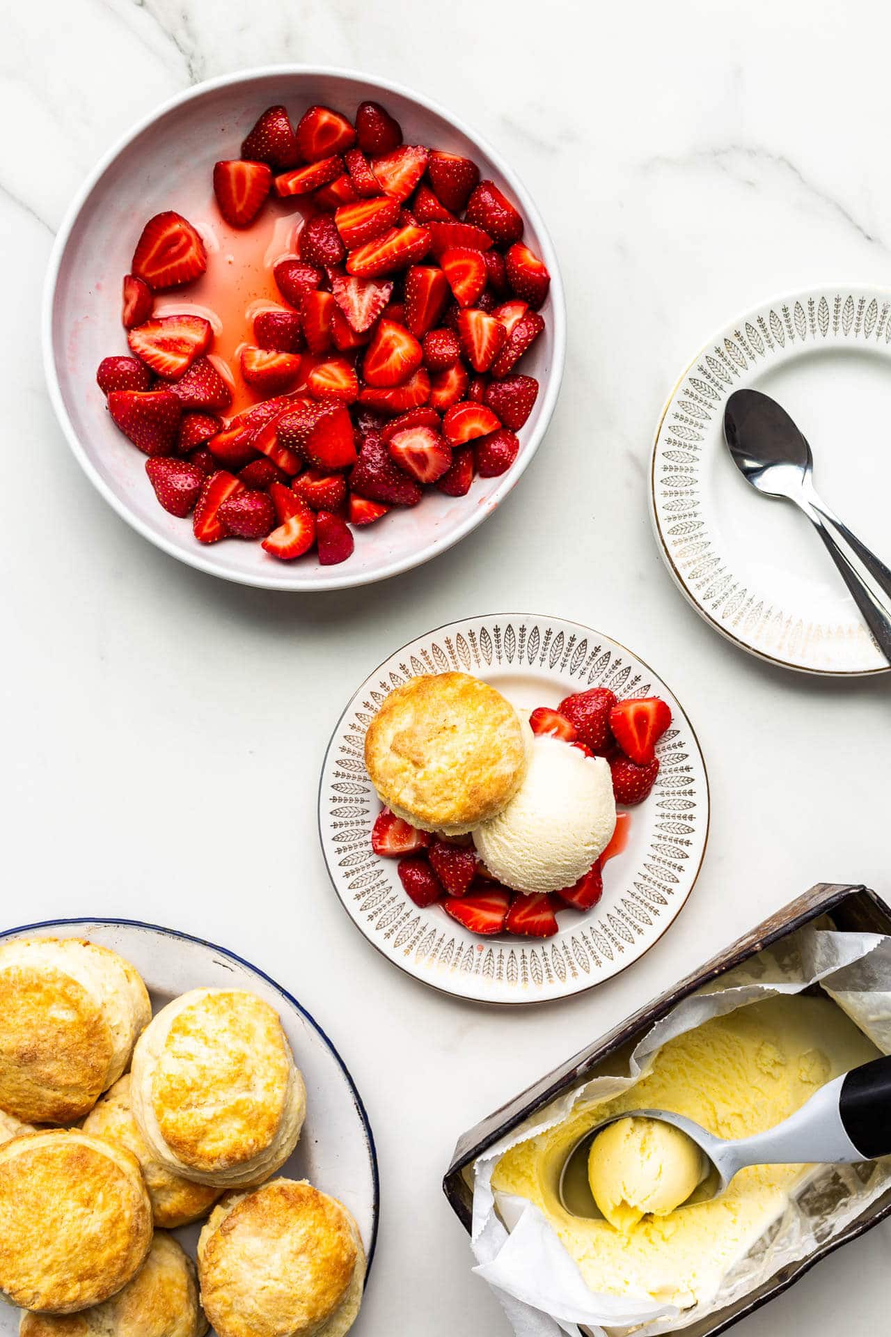 Serving strawberry shortcakes with biscuits, ice cream, and macerated sliced strawberries