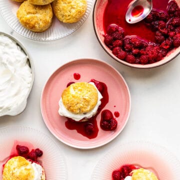 Assembling raspberry shortcakes with biscuits, macerated berries, and whipped cream
