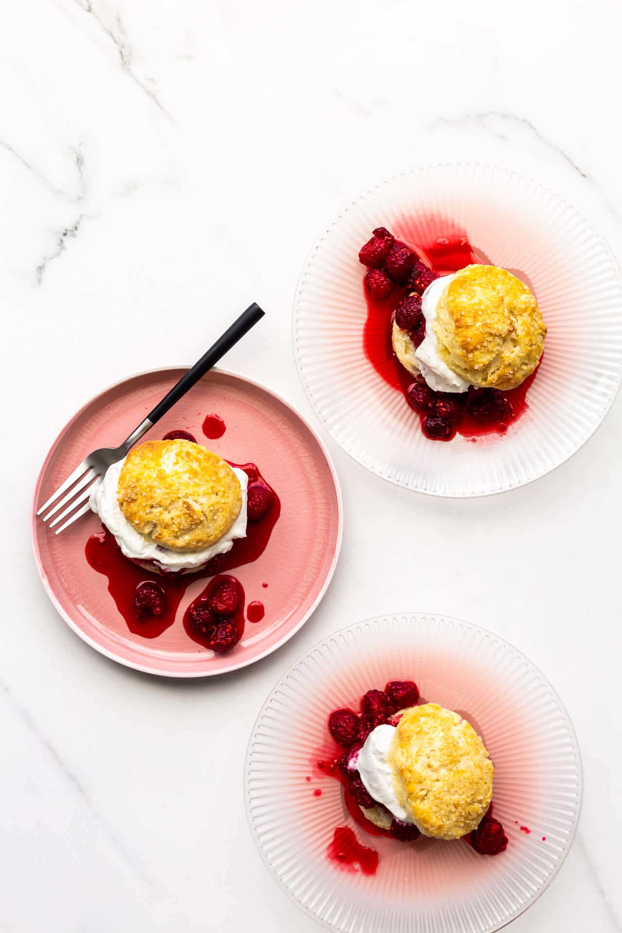 Three raspberry shortcakes served on pink plates