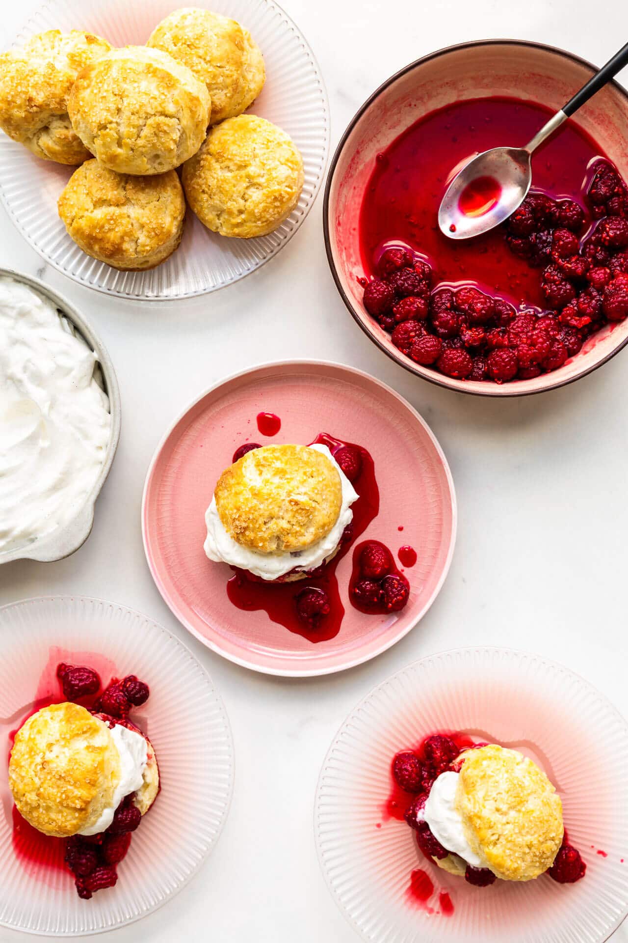 Assembling raspberry shortcakes with biscuits, macerated berries, and whipped cream